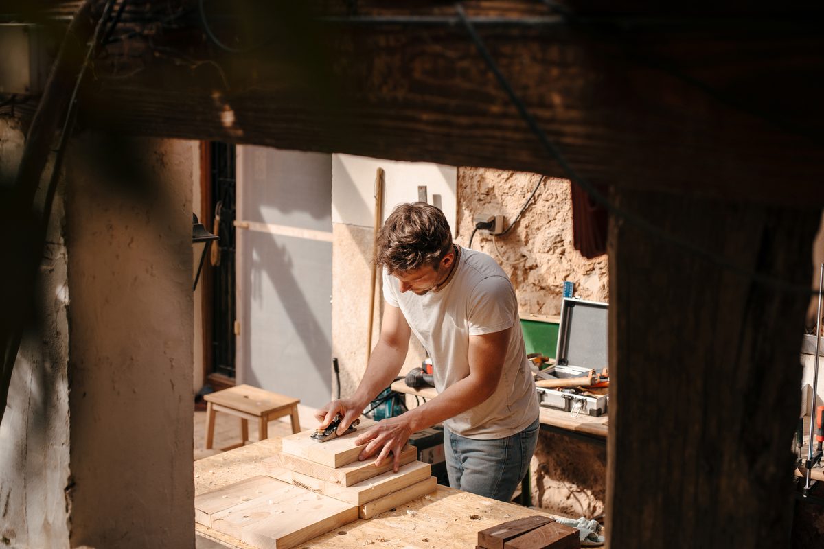 An Australian carpenter planing timber in his sunlit workshop — typical of the small-business owners we fund.