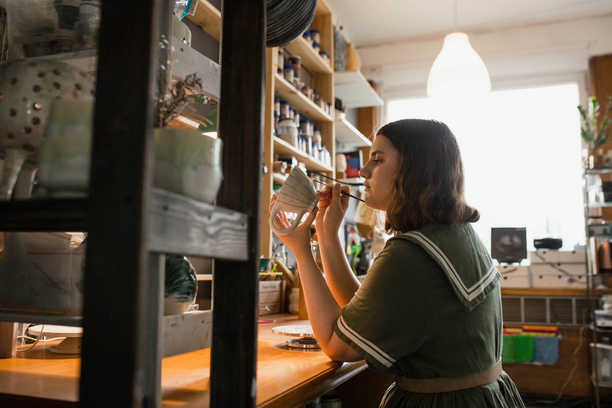 A ceramicist hand-painting a mug in her workshop — the kind of Australian small business we fund.
