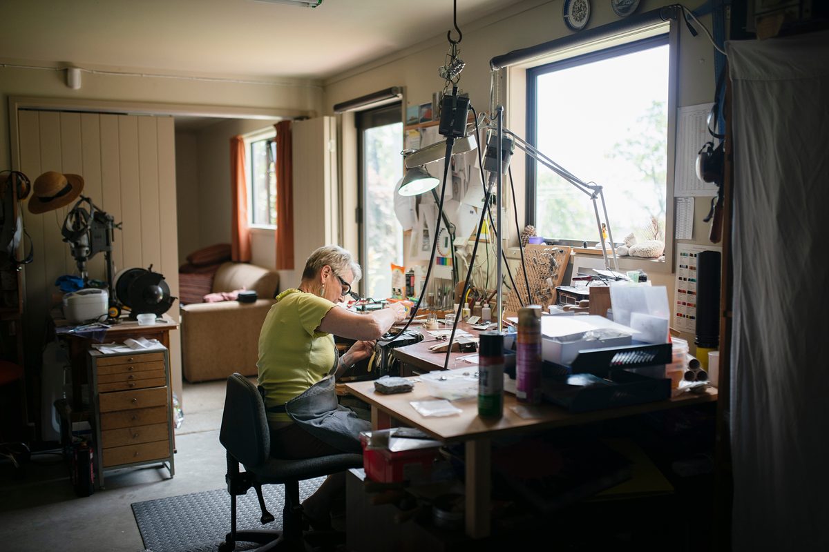An Australian jeweller working at her bench under a magnifier lamp — typical of the maker businesses we fund.